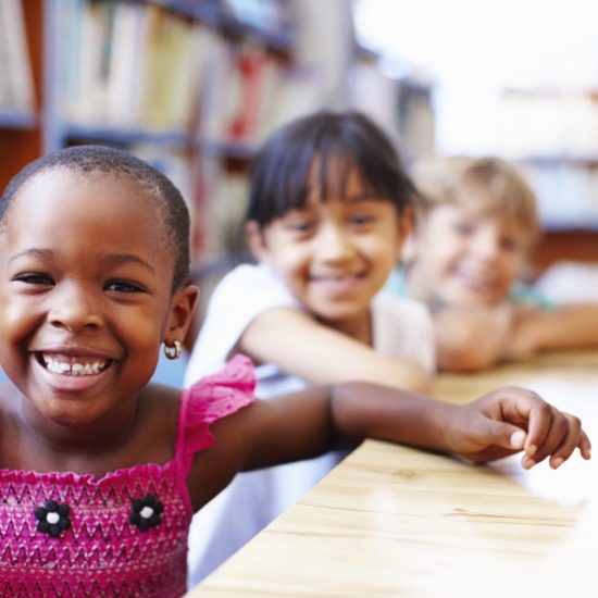 Portrait of a cute African American girl with friends in the library